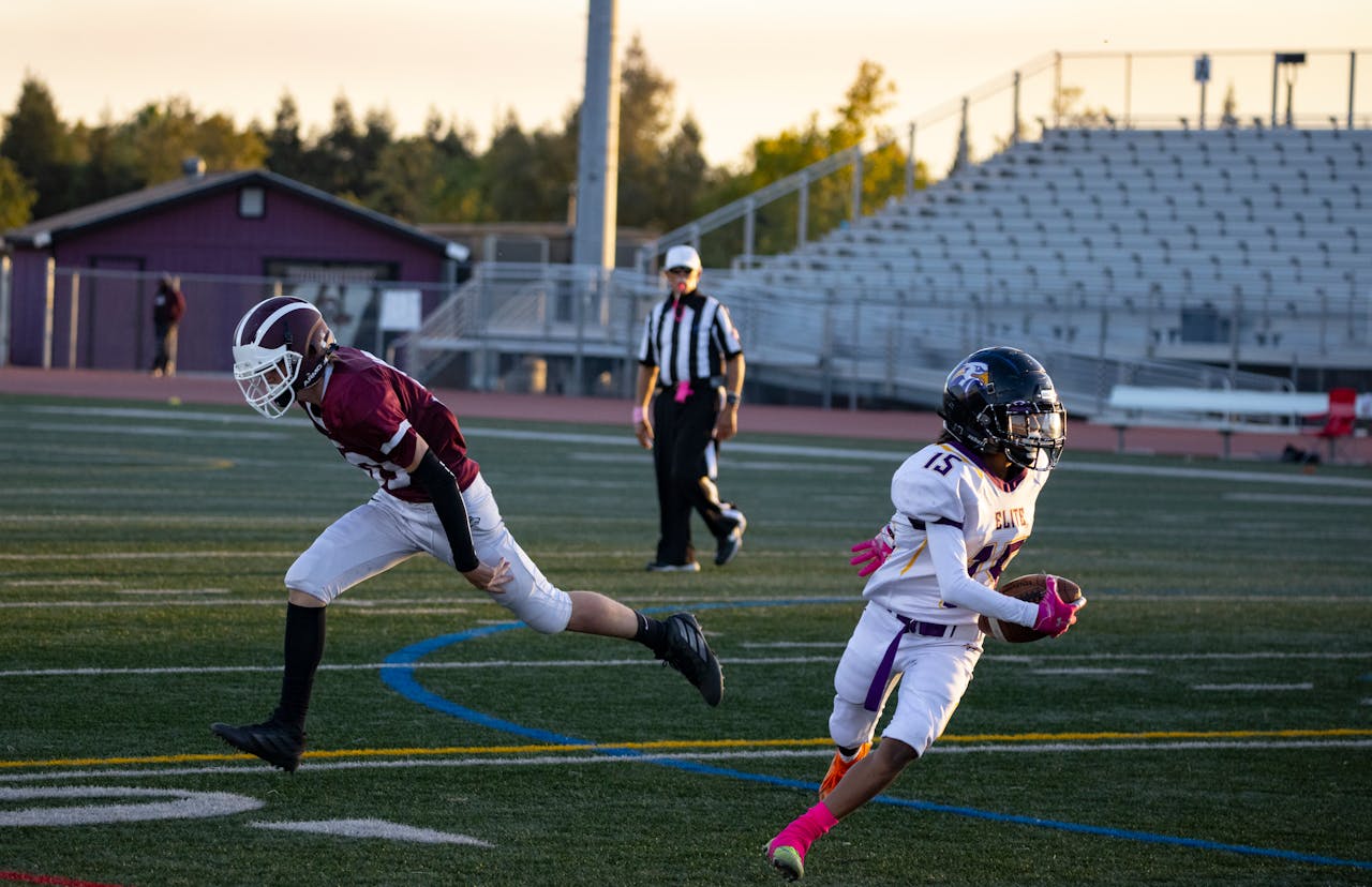 Youth football players in action on a field at sunset, showcasing athleticism and teamwork.